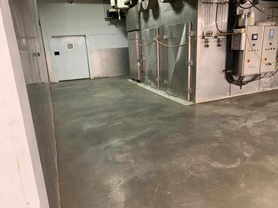A finished grey concrete floor extends around utility equipment and an interior doorway.