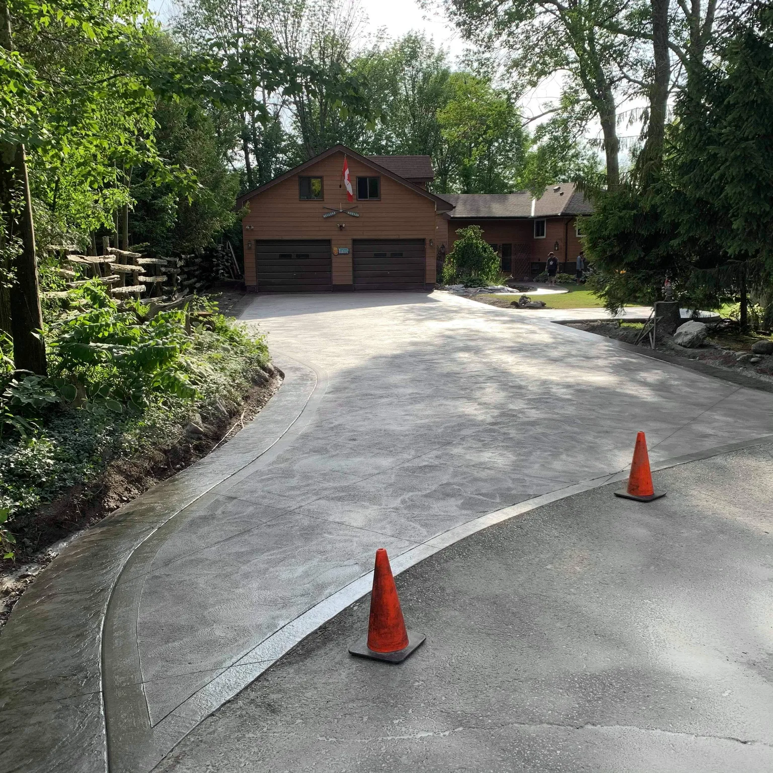 Concrete driveway approaching a cedar home surrounded by trees.
